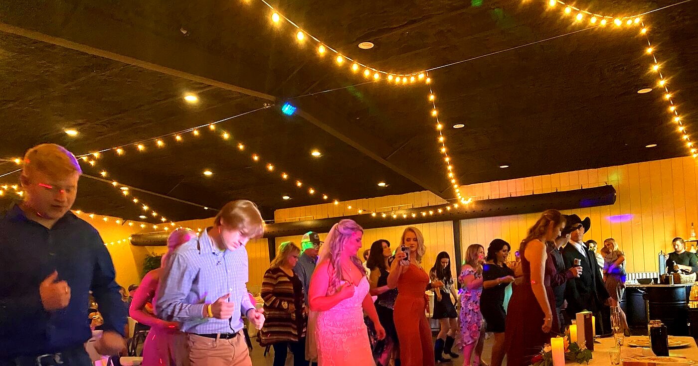 Packed wedding dance floor with colorful lighting
